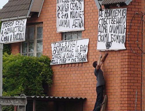 Владимир Ткаченко вывешивает плакаты на стену своего дома №25 по  улице Веселой в Адлере. 13 июля 2011 г. Фото С. Берестеневой