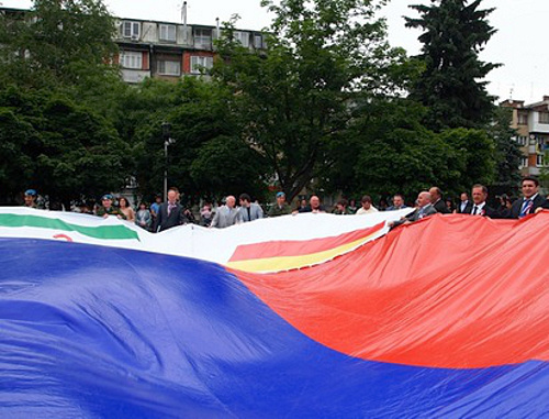 Участники автопробега "Эстафета Флага России" держат государственный флаг с пришитым к нему флагом Северной Осетии. Владикавказ, 10 июня 2013 г. Фото: http://region15.ru