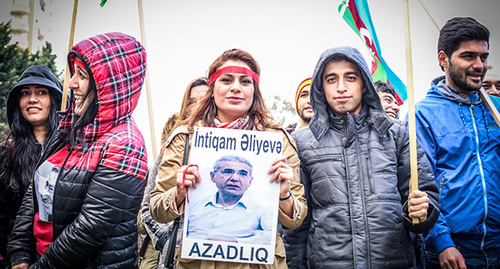 Участник акции держит в руках плакат с фотографией Интигама Алиева. Фото Азиза каримова для "Кавказского узла"