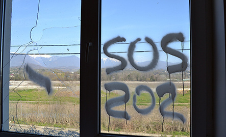 Надпись SOS на стекле разоренного коттеджа в поселке для переселенцев олимпиады "Веселое-Псоу" на границе с Абхазией. Фото Светланы Кравченко для "Кавказского узла"