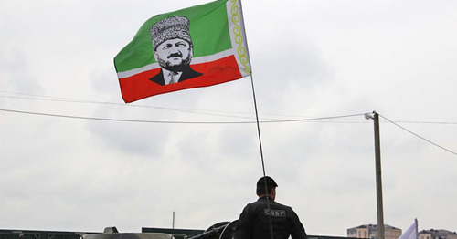 Сотрудник чеченского СОБРа с флагом республики, на который наложен портрет Ахмата Кадырова. 9 мая 2015 года, Грозный. Фото Магомеда Магомедова для "Кавказского узла"