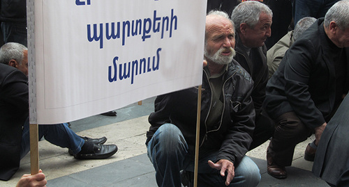 Участник акции протеста экс-сотрудников завода "Наирит". Надпись на транспаранте: "Погашение долгов по зарплате!". Ереван, 14 мая 2015 г. Фото Тиграна Петросяна для "Кавказского узла" Участник акции протеста экс-сотрудников завода "Наирит". Надпись на транспаранте: "Погашение долгов по зарплате!". Ереван, 14 мая 2015 г. Фото Тиграна Петросяна для "Кавказского узла"