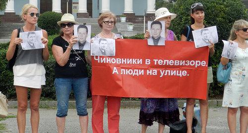 дольщики держат плакаты и портреты руководителя региональной инспекции Госстройнадзора и застройщика