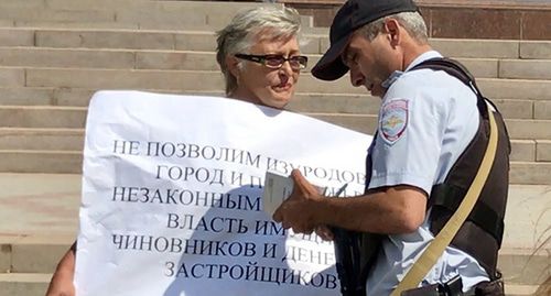 Сотрудник полиции проверяет документы у участницы акции. Фото Патимат Махмудовой для "Кавказского узла" Сотрудник полиции проверяет документы у участницы акции. Фото Патимат Махмудовой для "Кавказского узла"