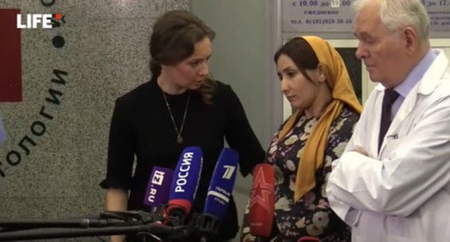 Президент по правам ребенка Анна Кузнецова, мама девочки и директор НИИ Леонид Рошаль (слева направо) во время интервью. Стоп-кадр видео https://life.ru/t/%D0%BF%D1%80%D1%8F%D0%BC%D0%B0%D1%8F%D1%82%D1%80%D0%B0%D0%BD%D1%81%D0%BB%D1%8F%D1%86%D0%B8%D1%8F/1263486/priamaia_transliatsiia_izbituiu_v_inghushietii_dievochku_aishu_vypisyvaiut_iz_bolnitsy Президент по правам ребенка Анна Кузнецова, мама девочки и директор НИИ Леонид Рошаль (слева направо) во время интервью. Стоп-кадр видео https://life.ru/t/%D0%BF%D1%80%D1%8F%D0%BC%D0%B0%D1%8F%D1%82%D1%80%D0%B0%D0%BD%D1%81%D0%BB%D1%8F%D1%86%D0%B8%D1%8F/1263486/priamaia_transliatsiia_izbituiu_v_inghushietii_dievochku_aishu_vypisyvaiut_iz_bolnitsy