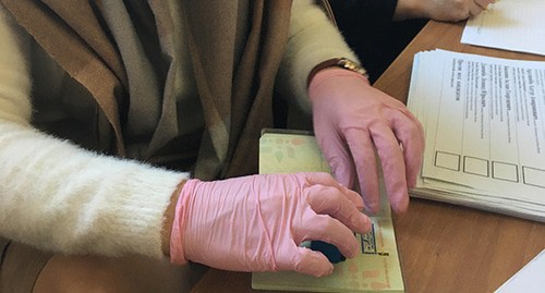 Член избирательной комиссии в медицинских перчатках ставит отметку о голосовании в паспорт. Сухум, 22 марта 2020 года. Фото Анны Грицевич для "Кавказского узла" Член избирательной комиссии в медицинских перчатках ставит отметку о голосовании в паспорт. Сухум, 22 марта 2020 года. Фото Анны Грицевич для "Кавказского узла"