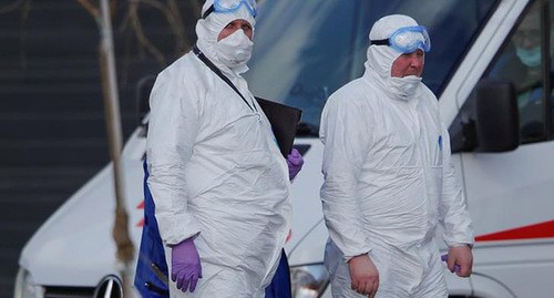 Медицинские сотрудники в защитных костюмах возле машины скорой помощи. Фото: REUTERS/Maxim Shemetov Медицинские сотрудники в защитных костюмах возле машины скорой помощи. Фото: REUTERS/Maxim Shemetov