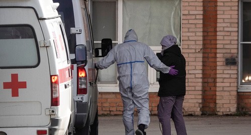 Медицинский работник в защитном костюме сопровождает пациента. Фото: REUTERS/Tatyana Makeyeva Медицинский работник в защитном костюме сопровождает пациента. Фото: REUTERS/Tatyana Makeyeva