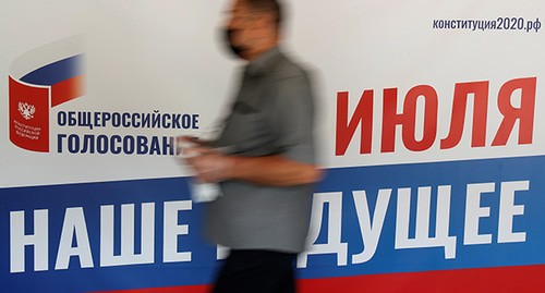 Человек на фоне плаката. Фото: REUTERS/Maxim Shemetov Человек на фоне плаката. Фото: REUTERS/Maxim Shemetov