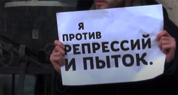 Плакат участника пикета против пыток. Скриншот видео https://www.youtube.com/watch?v=ixWMh8DMok4 Плакат участника пикета против пыток. Скриншот видео https://www.youtube.com/watch?v=ixWMh8DMok4