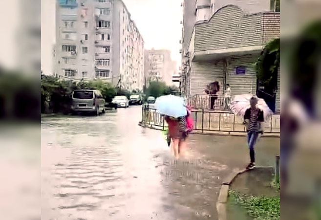 Жительница Краснодара переходит подтопленную улицу. Стоп-кадр из видео на странице https://vk.com/wall-33025155_10315557 Жительница Краснодара переходит подтопленную улицу. Стоп-кадр из видео на странице https://vk.com/wall-33025155_10315557
