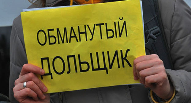 Женщина держит в руках плакат: "Обманутый дольщик". Фото: https://riadagestan.ru/news/the_people_s_assembly/edinaya_rossiya_zapustila_onlayn_priemnuyu_dlya_obrashcheniy_obmanutykh_dolshchikov/ Женщина держит в руках плакат: "Обманутый дольщик". Фото: https://riadagestan.ru/news/the_people_s_assembly/edinaya_rossiya_zapustila_onlayn_priemnuyu_dlya_obrashcheniy_obmanutykh_dolshchikov/